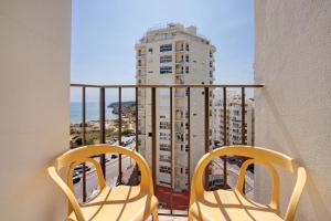 two chairs on a balcony with a view of a building at Casa Ferrão in Armação de Pêra