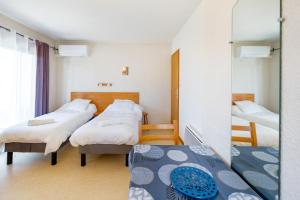 a room with three beds and a mirror at Les Mimosas - Appartement 05 in Cazaubon