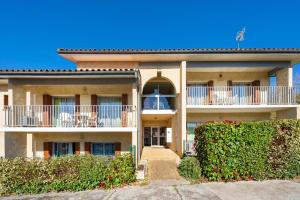 an apartment building with a balcony and bushes at Les Mimosas - Appartement 05 in Cazaubon