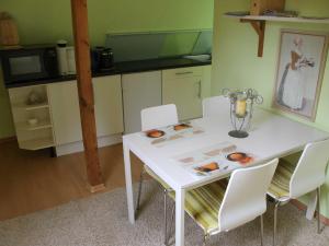 a kitchen with a white table and white chairs at Ferienwohnung an der Müritz in Klink