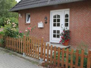 a house with a wooden fence and a white door at Ferienwohnung an der Müritz in Klink