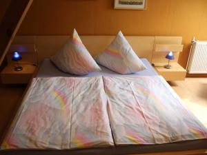 a bed with white sheets and colorful pillows on it at Ferienwohnung an der Müritz in Klink