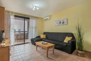 a living room with a black couch and a table at Palm Serenity in Playa Paraiso