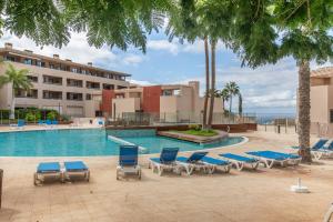 a swimming pool with lounge chairs and a hotel at Palm Serenity in Playa Paraiso