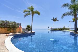 a large swimming pool with palm trees and the ocean at Casa Fuentes 2 B2 in Almuñécar