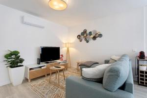 a living room with a blue couch and a tv at Coral Beach Oasis in Figueira da Foz