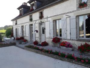 a white building with potted flowers in front of it at Chambres d'hôtes Chez Mathilde in Eaux-Puiseaux