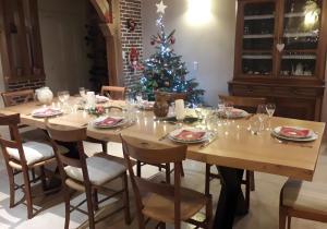 a dining room table with a christmas tree in the background at Chambres d'hôtes Chez Mathilde in Eaux-Puiseaux +23 photos