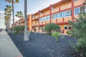 an orange building with palm trees in front of it at Los Tinajones in La Oliva