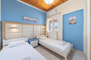two beds in a room with blue walls at Eli Guesthouse in Kavos