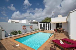 a swimming pool on a patio with a house at Villa Calima Deluxe con Piscina in Tías