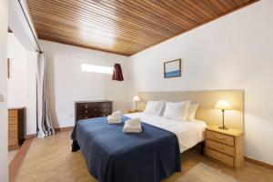a bedroom with a large bed with a blue blanket at A Cerca - A in Lagos