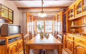 a dining room with a wooden table and a tv at Ca La Rosalia in El Pla de Manlleu
