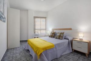a bedroom with a bed with a yellow blanket on it at Casa Relax in Gran Tarajal