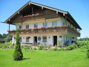 a large house with a balcony on a green field at Schwaigerhof in Grassau