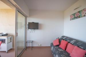 a living room with a black couch and a tv at Résidence Aria Marina Plage in Ajaccio