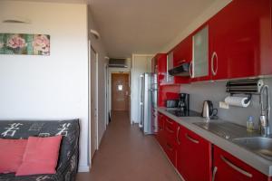a red kitchen with red cabinets and a sink at Résidence Aria Marina Plage in Ajaccio