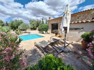 an umbrella and chairs next to a swimming pool at Casa Cascada in Costitx