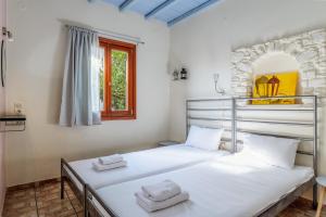 two beds in a room with a window at En Tino 2 in Tinos