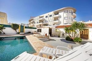 a swimming pool with white chairs and a building at A Cerca - A in Lagos