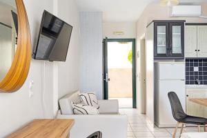 Eine Küche mit einem an der Wand befestigten Fernseher und Stühlen in der Unterkunft Sunset Premium Studio B in Lefkada Town