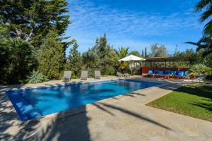 a swimming pool in a yard with chairs and an umbrella at La Vila Ibiza in Sant Josep de sa Talaia
