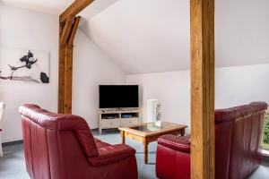 a living room with two red chairs and a tv at Ferienwohnung Ebbe am Weserstrand in Sandstedt