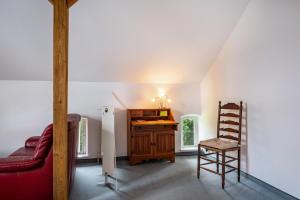 a living room with a red couch and a wooden chair at Ferienwohnung Ebbe am Weserstrand in Sandstedt