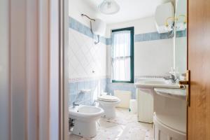 a white bathroom with two toilets and a sink at Su entu a mari Museddu in Cardedu +15 photos