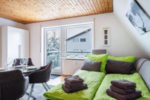 a living room with a green couch and a table at Schwarzwaldblick D App 10 mit Pool in Schönwald