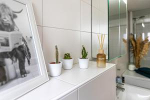a white bathroom with plants in white pots on a counter at Ferienwohnung Carolin Witt in Großsolt