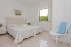 a white bedroom with a bed and a chair at Biniforcat 21 in Cala en Forcat +15 photos