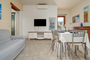 a living room with a table with chairs and a tv at Trilo La Rosa in Monte Petrosu