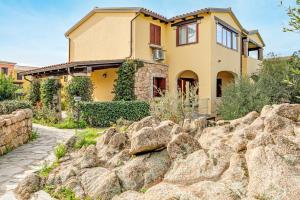 a yellow house with a rock fence in front of it at Trilo La Rosa in Monte Petrosu