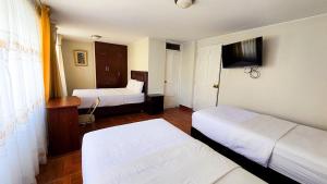 a hotel room with two beds and a television at Hotel Palmeras Tacna in Tacna