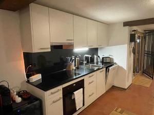 a kitchen with white cabinets and a black counter top at Escape Private SPA II in Bad Zurzach