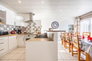 a kitchen with white cabinets and a counter with chairs at Gite Augustine Aux Charmes D'antan in Sevremont