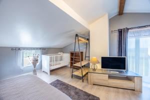 a bedroom with a bed and a tv and a crib at Gite Augustine Aux Charmes D'antan in Sevremont