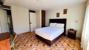 a bedroom with a white bed and a wooden floor at Hotel Palmeras Tacna in Tacna