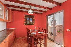 a kitchen with red walls and a wooden table and chairs at Villa Florymar in Ingenio
