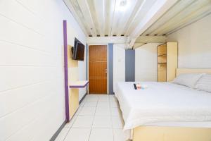 a small bedroom with a bed and a tv at Simple Hotel Bogor RedPartner in Bogor