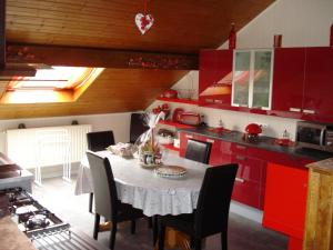 a kitchen with red cabinets and a table with chairs at Le Gite Fleuri in Hazelbourg