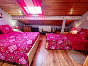 two beds in a room with pink comforter at Le Gite Fleuri in Hazelbourg