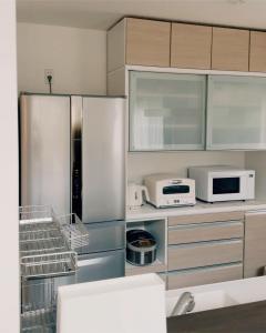 a kitchen with a stainless steel refrigerator and microwave at Chigasaki Southern Beach House 茅ヶ崎サザンビーチハウス in Chigasaki