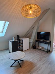 a living room with a table and a tv at Chambre D'hôte - La Capucine in Bazouges