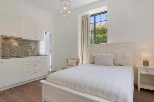 a white bedroom with a bed and a window at Vila Francisco in Funchal