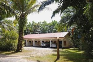 a house with two palm trees in front of it at 057 รีสอร์ท in Ban Huai To