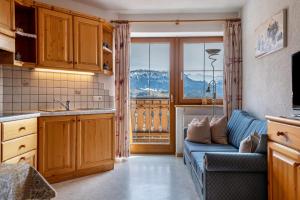 a living room with a blue couch and a kitchen at Malsötscherhof Apt B in Villandro