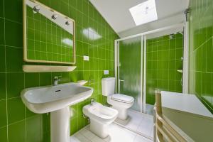 a green bathroom with a sink and a toilet at Villa Liberty Rosa 1912 in San Vincenzo +22 photos
