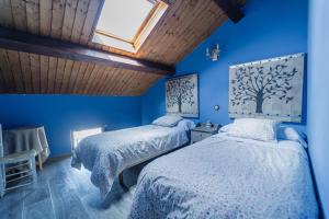 two beds in a blue bedroom with a skylight at El Palomar De La Cuesta in Lerma